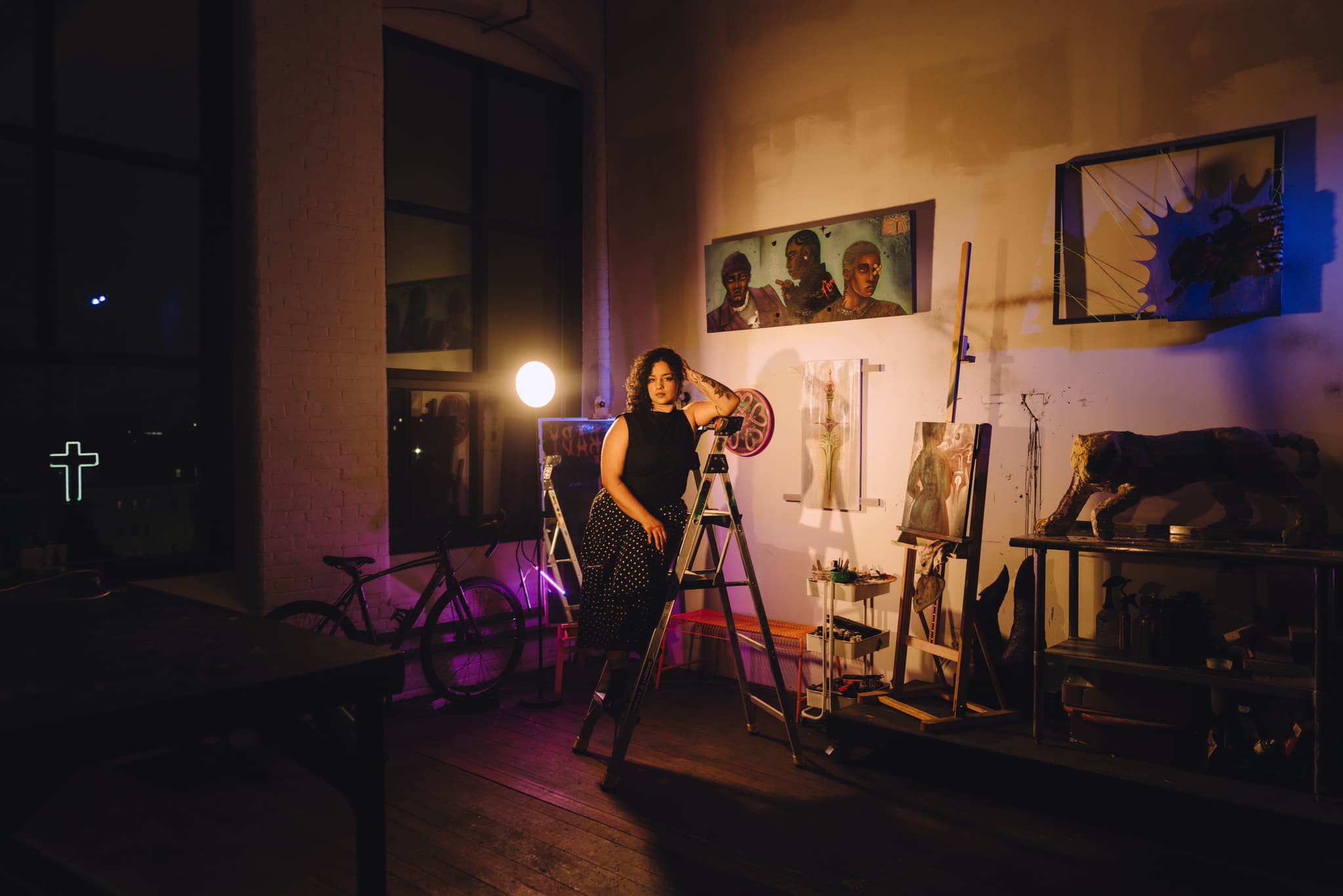 An artist rests on a ladder in her studio for a portrait.