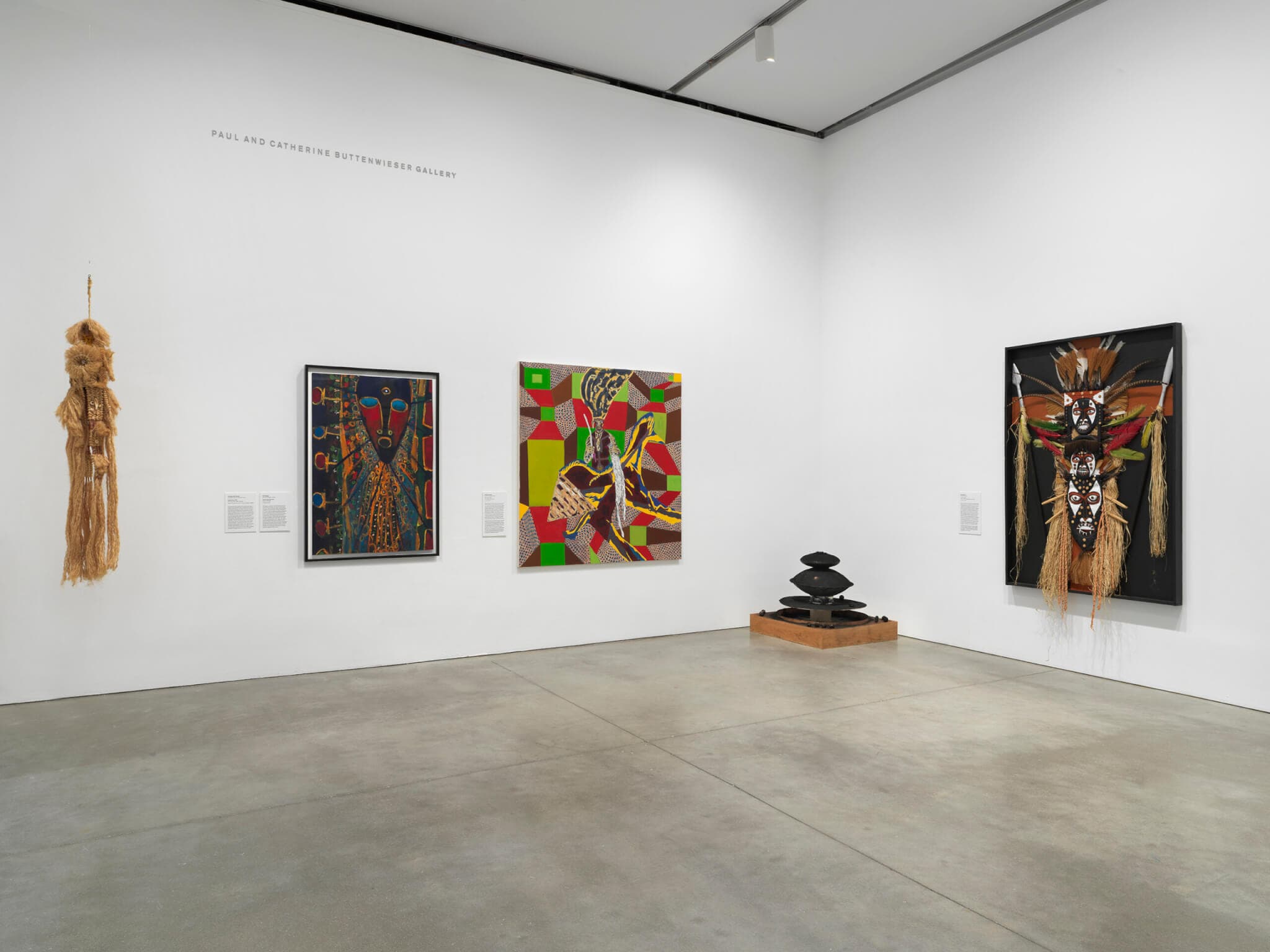 Large artworks in brown, green, and red hues hang on white gallery walls.