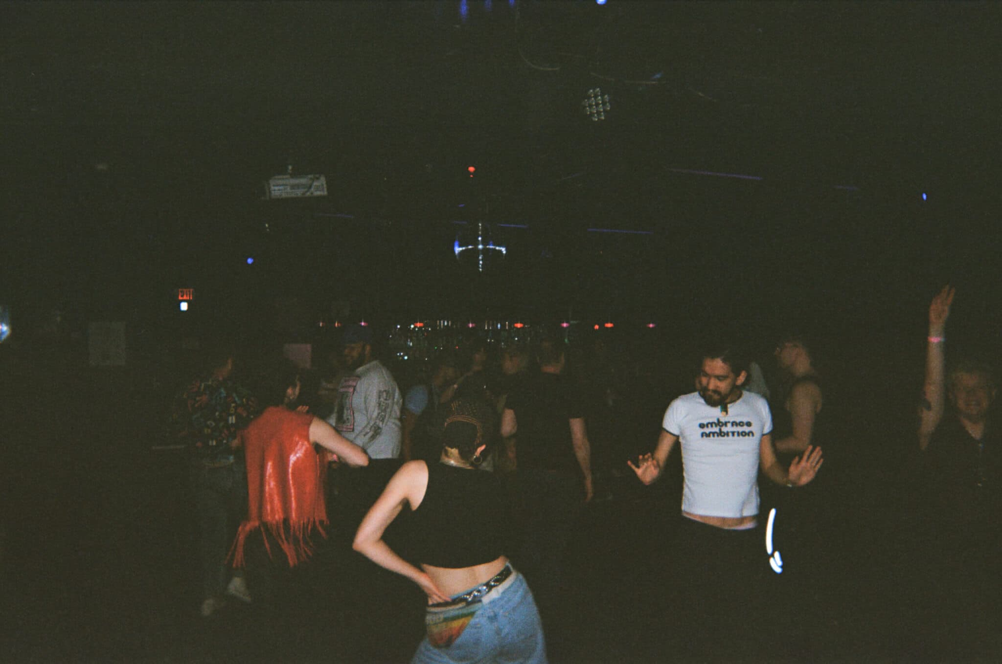 A darkened nightclub scene that depicts a group of people dancing.