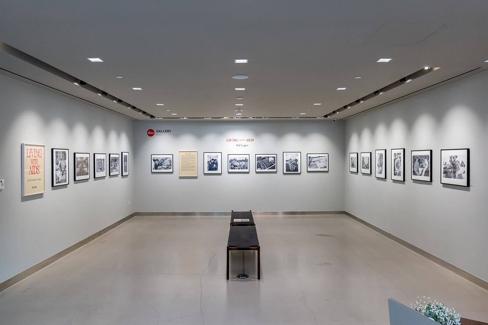 Black-and-white photographs line three walls of a gallery.